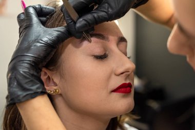 Kız, kaşlarının dezenfekte edilmiş cımbızla alındığı salonda oturuyor. Kaş düzeltici kirletici