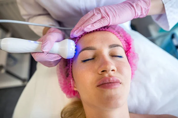 a girl at an appointment with a beautician is doing an ultrasonic face cleaning. Ultrasonic cleaning is hardware cleaning that is carried out with the help of high-frequency ultrasonic waves.