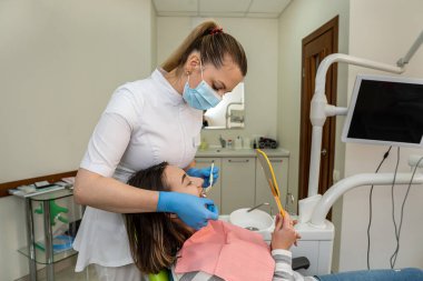 Diş hekiminde beyazlatıcı tedavisi için örnekler var. Sonuç olarak hasta kadının gölgesini seçiyor. Diş beyazlatma, bakım ve hijyen