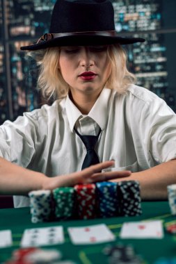 Poker masasında şapkalı ve kravatlı güzel satıcı kız. Süreci takip et. Oyun. Aldatmaca. entrikalar