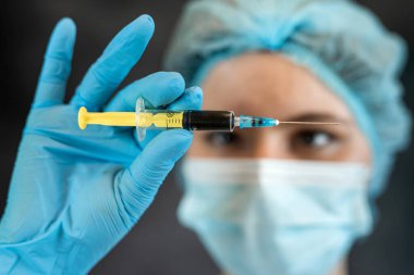 Koruyucu giysiler içinde kadın doktor elinde şırınga, tıbbi sağlık konsepti