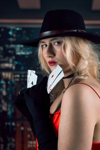 美しい若い女性は赤いドレスと黒の帽子を着用エースポーカーカードを保持します カジノでのギャンブル — ストック写真
