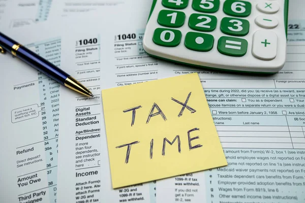 メモ付きのテキストTax Timeは机の上にペン計算機で1040を形成します 会計課税の概念 — ストック写真