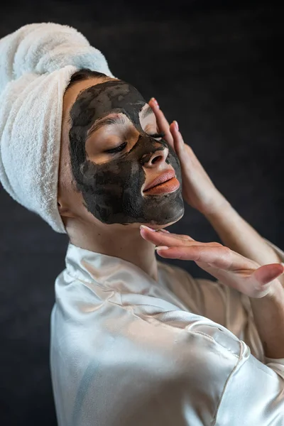 Piękna Młoda Kobieta Czarnej Glinianej Masce Odizolowana Czarno Leczenie Twarzy — Zdjęcie stockowe