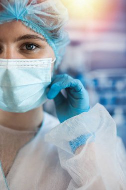Ameliyathanede ameliyat maskesini takan kadın cerrah ya da asistanın portresi. Coronavirus Covid19 salgını