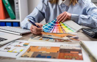 Kadın tasarımcı ev planı ve renk paleti örnekleriyle çalışıyor. İç çizimler ve ev dekorasyonu planları.