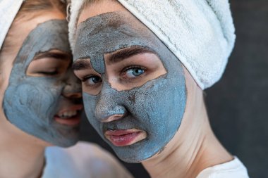 Siyaha izole edilmiş kilden siyah maske takan iki güzel kız. Evde yüz derisine dikkat et. Yaşam biçimi