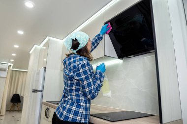 beautiful young girl in a scarf is doing general cleaning in her kitchen. Kitchen cleaning concept. purity