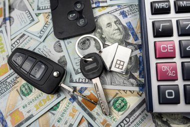 Ev ve araba anahtarlarının üzerinde hesap makinesi olan dolar parası, gelecekte yatırım, satın alma ya da kira konsepti