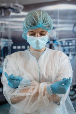 Ameliyat odasında koruyucu bez maske takan genç kadın cerrahın portresi. Sağlık çalışanı.