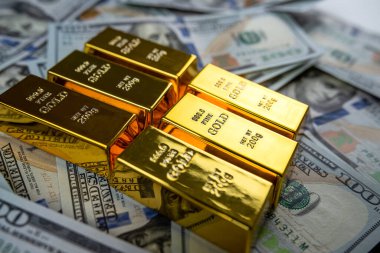 closeup gold bar lying on 100 dollar bills. Gold bullion and money concept