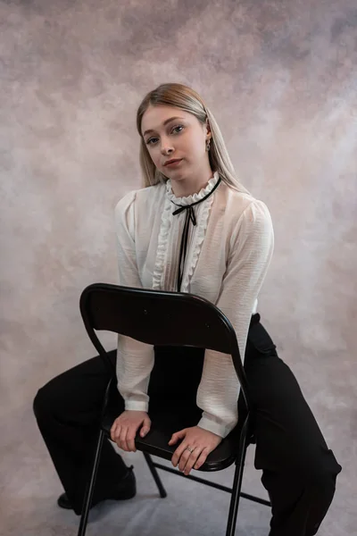 Hübsches Weibliches Model Trägt Weiße Bluse Und Schwarze Hose Sitzt — Stockfoto