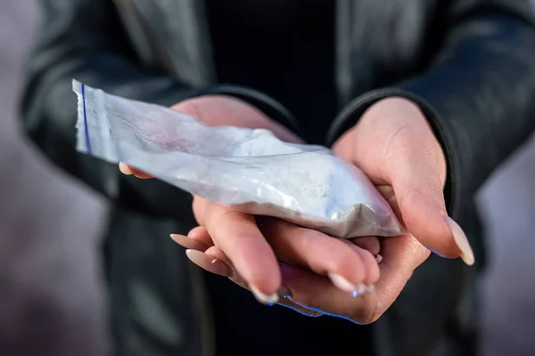 stock image closeup of drug dealer wear black cloth hold packet of heroin or cocaine. Drug abuse concept