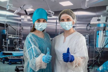 İki hastane çalışanı, bir kadın cerrah ve bir hemşire hastanede kollarını kavuşturmuş bekliyorlar. Sağlık ve doktor hizmetleri.