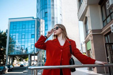 İş kadını ofisin yakınındaki iş adamlarıyla telefonda konuşuyor. Ofis çalışanı mutlu gülümsüyor. Profesyonel bir kadın..