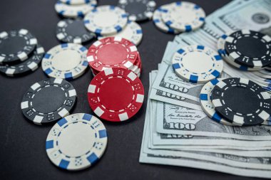 Kağıt, fiş ve dolar yeni poker masasının etrafına saçıldı. Şansın siyah arka plan oyununda izole edilmiş. Poker konsepti.