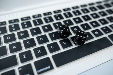 Siyah bir masada izole edilmiş yeni bir dizüstü bilgisayarın beyaz klavyesindeki siyah küpleri. Yukarıdan bak. Çevrimiçi kumar ve kumarhane kavramı. zar kapat