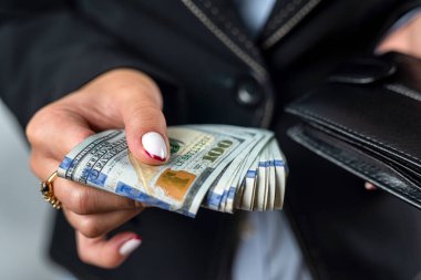 Genç kız elinde büyük bir miktar para tutuyor ve kara bir çantada para sayıyor. Para ve cüzdan. Kadın sağlandı. bolluk