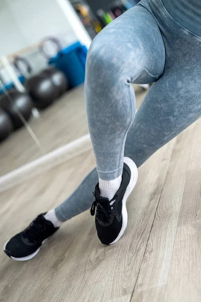 sportswoman in sports leggings and cross-legged flaunts her athletic skinny legs. sport. cropped photo. girl