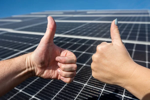 close up posing with positive gesture on photovoltaic solar panel and thumbs up. the concept of the idea of ??saving money and clean energy