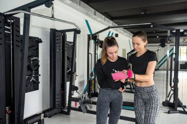 Kişisel antrenör ve antrenör kadın spor salonundaki bir güzelliğe yardım ediyor. Sağlıklı yaşam tarzı. Bir profesyonelle eğitim.