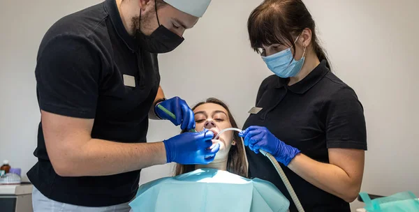young girl laughs at a dentist examination with an assistant in a dental clinic. a dentist and an assistant conduct an examination. healthy oral cavity