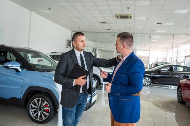 Müşteri araba galerisinde profesyonel bir erkek yöneticiye yardım ederek modern bir araba alıyor. Başarı anlaşması kavramı