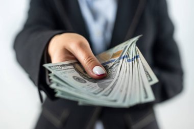 Klasik ceketli kendine güvenen kız dolarları nakit olarak gösteriyor. Kağıt para. Pasif gelir ve zenginlik. Nakit para