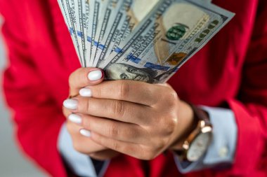 Beyaz gömlekli, kırmızı ceketli ve arka planda izole edilmiş nakit para hayranları tutan bir kadın. Para konsepti. İş. Nakit kar. Dolarlar hazır.