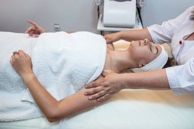 strong female masseur is doing a cosmetology facial massage to a client. spa salon concept. facial skin tightening