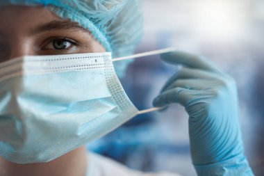 Genç kadın doktor cerrahlar ameliyat odasındaki kameraya bakarak pozisyonlarını alıyorlar. Sağlık ve Tıp Konsepti.