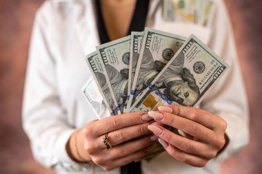 Cropped photo of a woman holding US dollar money in her hands on the background of her body. isolated on plain background. budget planning. the concept of profit
