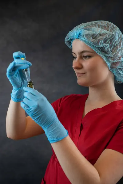 stock image young nurse in protective cloth holding syringe on dark background, medical worker. Healthcare