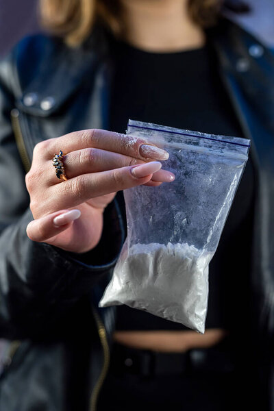 female hand wear dark clothes holds bag with cocaine