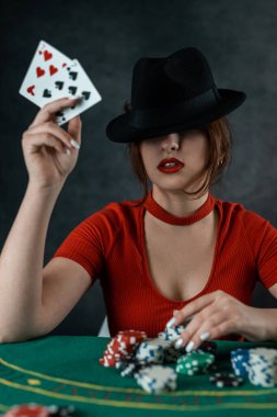 Kadının eli yuvarlak yeşil bir poker masasında poker kartı alıyor. Pokerde riskli bahisler. Poker kumarhanesindeki kadın