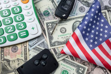 Arka planda iki siyah araba anahtarı olan bir hesap makinesi. Otomatik kiralama veya satın alma