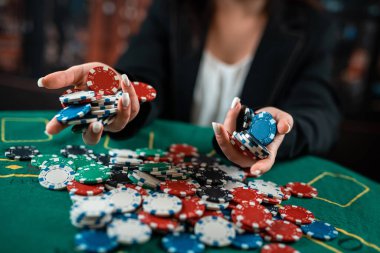 Kırmızı elbiseli kız bir avuç dolusu renkli poker fişi poz veriyor. Poker. Kumarhane Yakından.