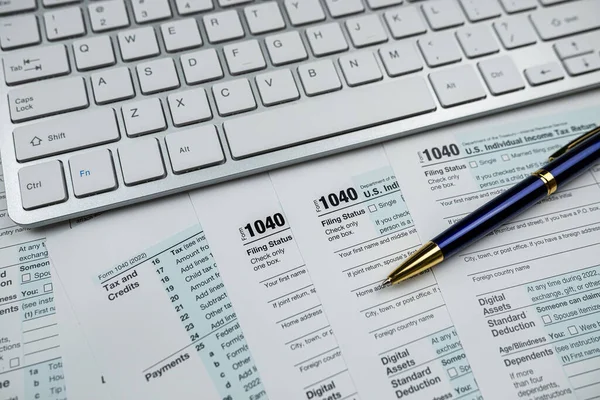 pen with computer keyboard on business finance tax form, office desk. Paperwork deadline concept