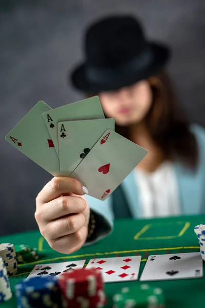 美しい女の子は広い緑のテーブルでポーカーをするために夜のカジノに来ました 帽子を被った女性だ ポーカーゲームの興奮 大金だ — ストック写真