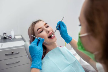 Bir dişçi tarafından tedavi edilirken gülümseyen bir kadının ağzının fotoğrafı. Diş sağlığı konsepti.