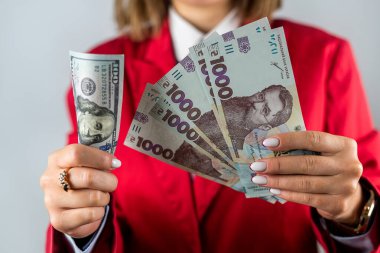 Çok sayıda dolar, yakın çekim ve güzel genç bir kadının ellerinde hryvnialar. İş ve zenginlik kavramı. Eldeki para
