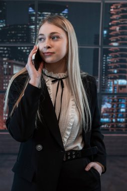 Güzel bayan işçi ofiste duruyor ve telefonda konuşuyor. Moda portresi