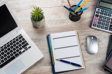 Ofis masası geçmişi, dizüstü bilgisayarı, boş not defteri, kalem hesap makinesi ve malzemeleri. Üst görünüm, iş geçmişi