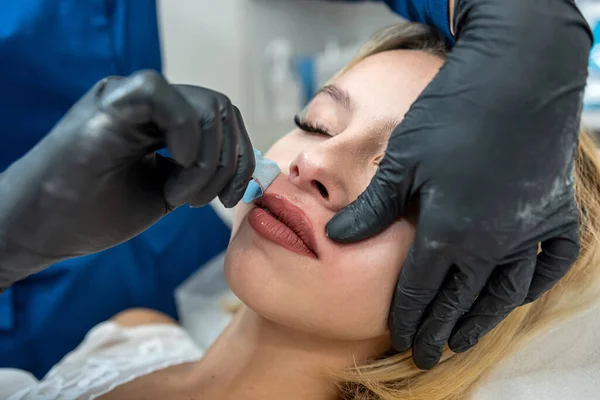 master applying cosmetics gel wax upper lip before hair removal procedure in clinic. Cosmetology procedure with sugar and wax. Sugaring. Depilation
