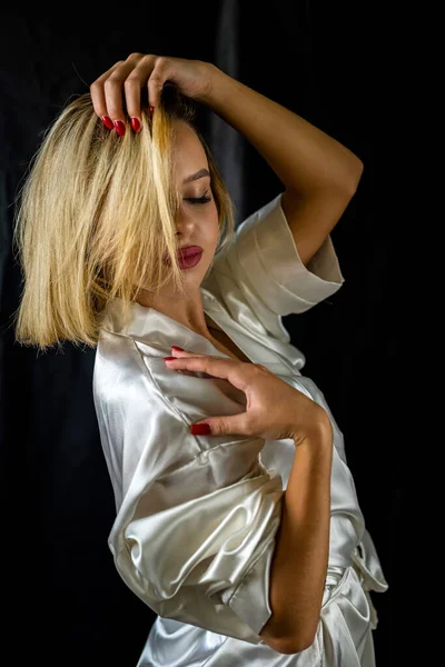 純白の暗い背景に身を包んだ魅惑的なパジャマ姿のセクシーな上品なセクシー女の子 孤立したスタジオの肖像画です — ストック写真