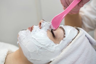 Genç ve güzel bir kadın spa kliniğinde estetik ameliyat oluyor. Deri ve vücut bakımı için yüzünde beyaz maske var. Yaşam biçimi