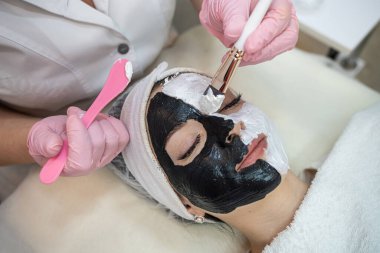 Kaplıca salonundaki siyah beyaz maskeli kadın. Güzellik prosedürleri. Cilt bakımı