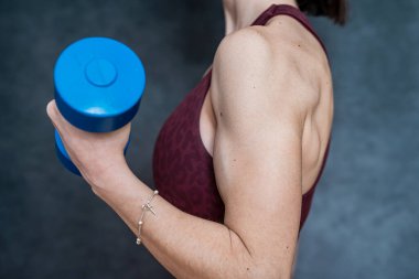 Çok ince bir kız, elinde dambıl tutuyor ve sabah egzersizi yapıyor. Sağlıklı bir yaşam için siyah bir spor.