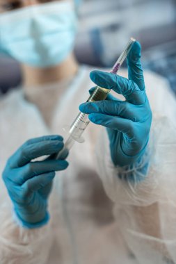 Doktor kadın anestezi uzmanı ameliyattan önce ameliyathanede bir iğne hazırlıyor. Tıbbi sağlık konsepti