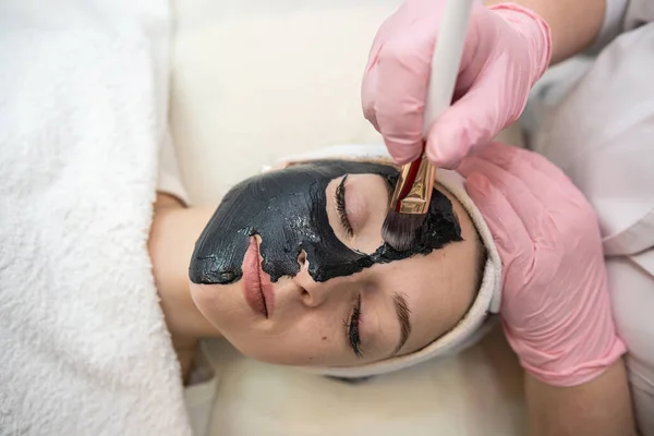 Giovane Bella Donna Riceve Maschera Facciale Cosmetica Nera Salone Bellezza — Foto Stock